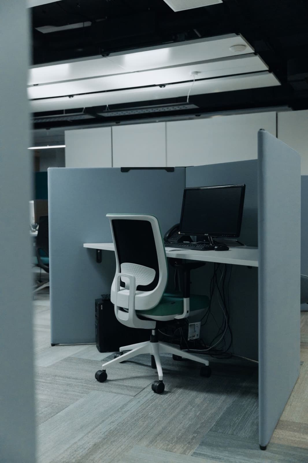 Empty modern office cubicle with a computer and swivel chair ready for work
